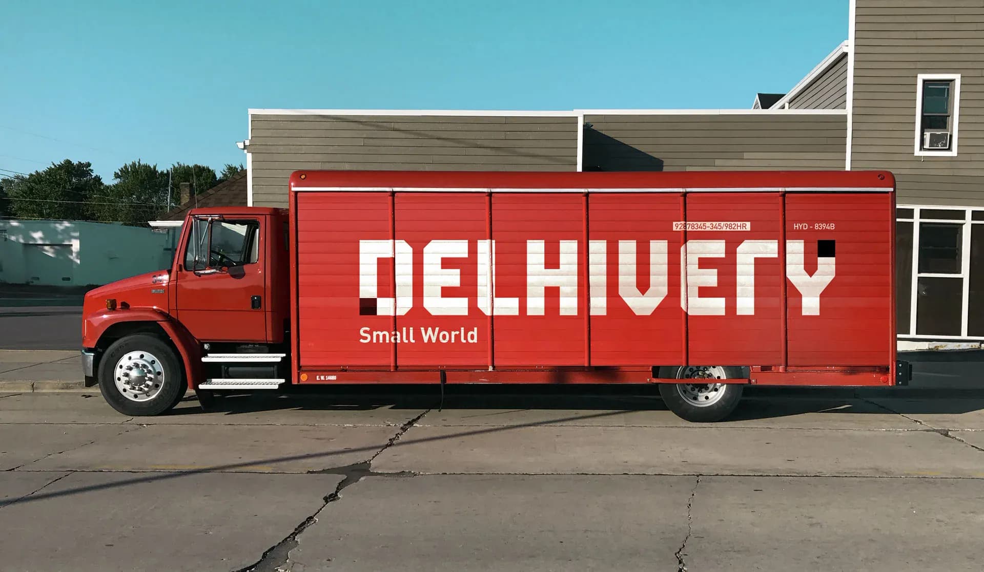 Red Delhivery truck with the Small World wordmark