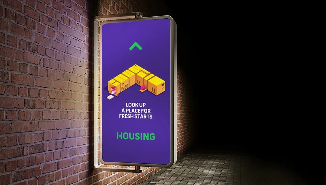 Housing.com lightbox ad on a brick wall at night