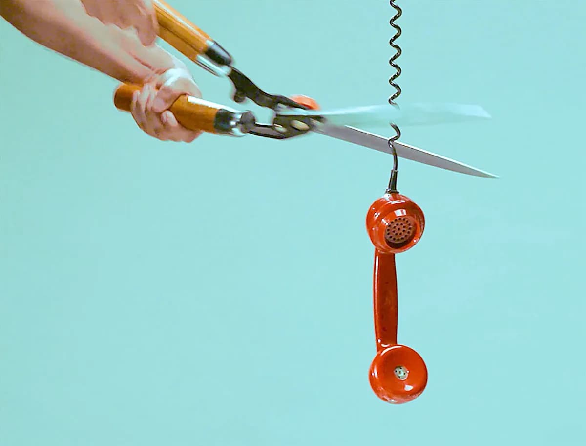Scissors cutting a red phone cord, OnePlus campaign still