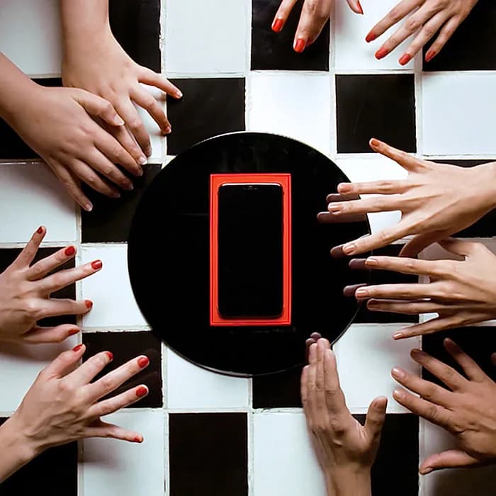 Hands reaching for a red phone on a checkerboard, OnePlus campaign